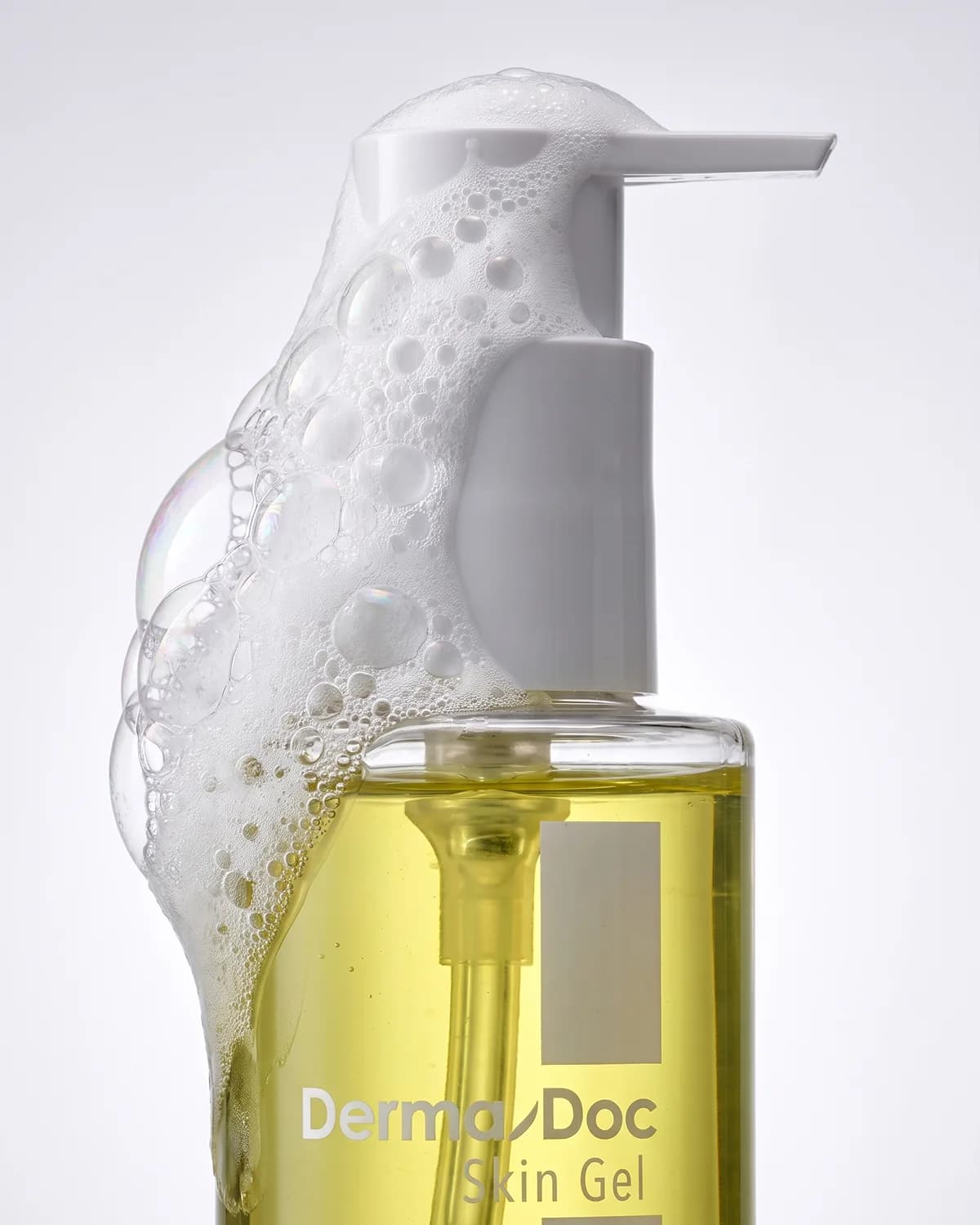Mousse débordant du flacon de gel nettoyant DermaDoc Skin Gel.