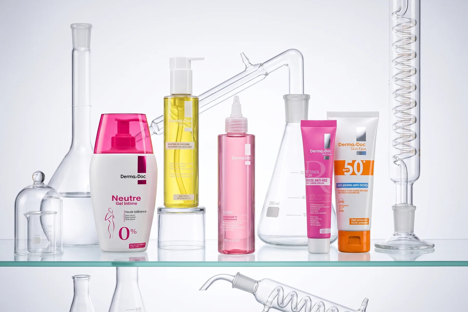 Gel Intime Neutre, gel nettoyant, toner, rétinol pur et écran solaire DermaDoc parmi de la verrerie de laboratoire.